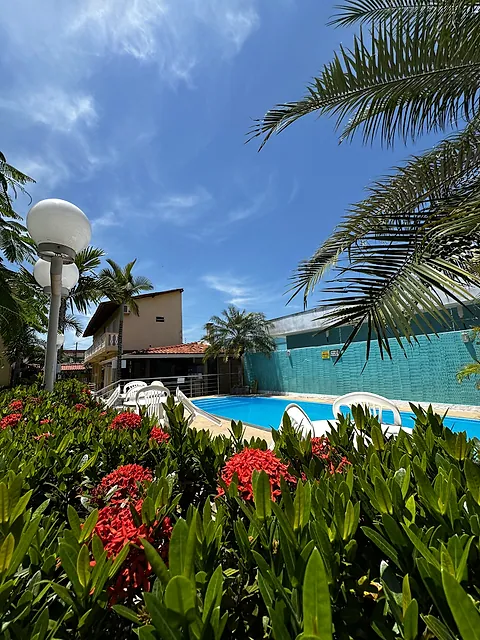 Flores vermelhas em primeiro plano e a piscina ao fundo