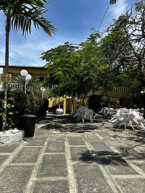 Pátio arborizado com mesas e cadeiras