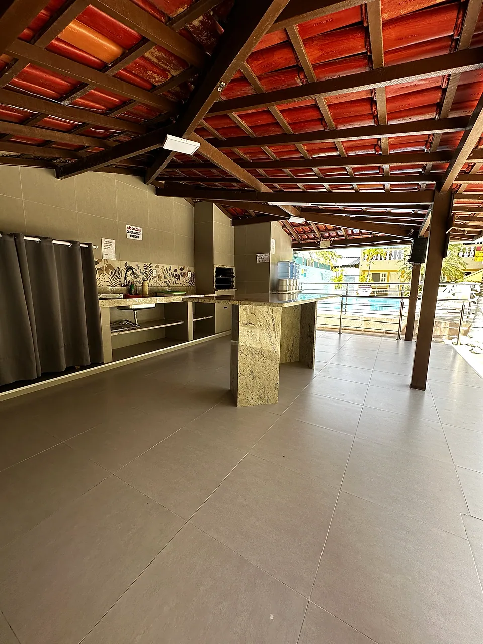 Área gourmet coberta com bancadas e vista para a piscina