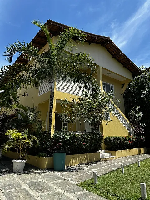 Prédio da pousada com palmeira e jardim