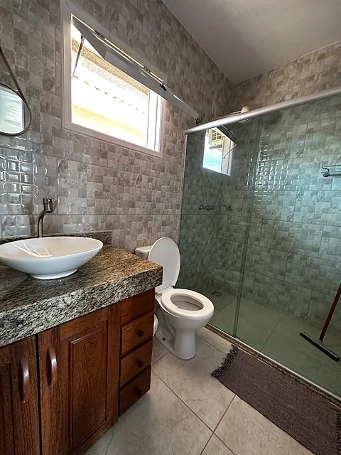 Banheiro com box de vidro e bancada de granito