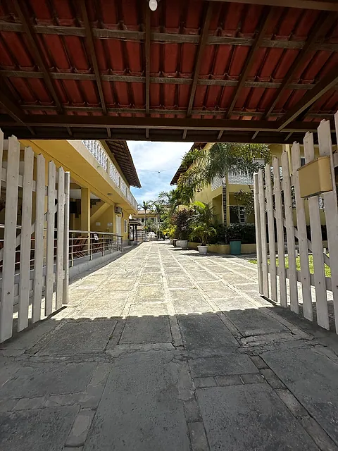 Portão de entrada com corredor ladeado de plantas
