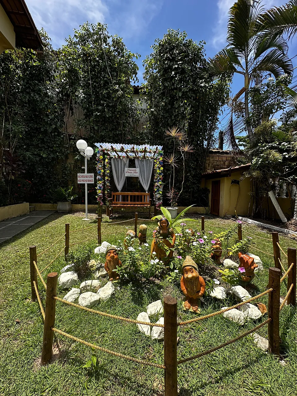 Jardim gramado com canteiro de flores e caramanchão